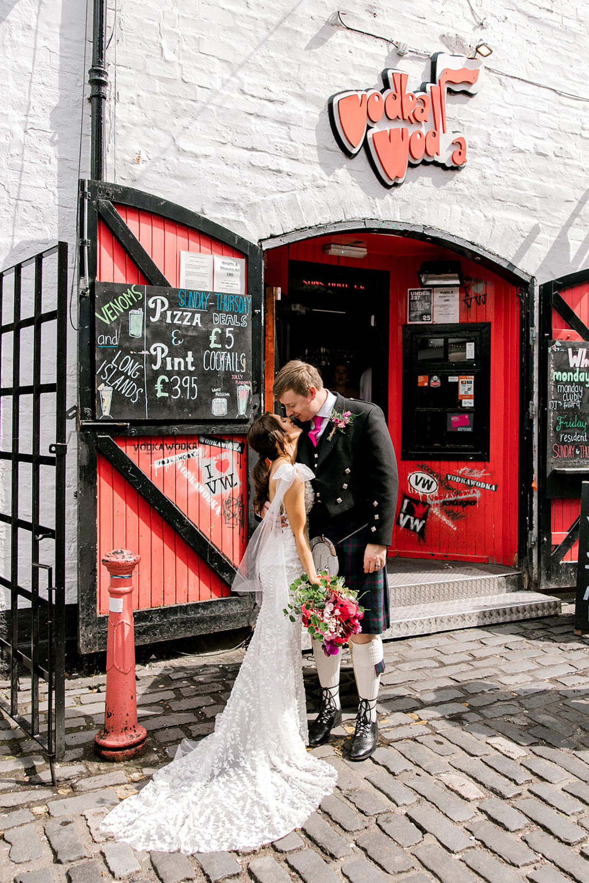 Bride and groom kissing outside a colourful Glasgow city centre bar