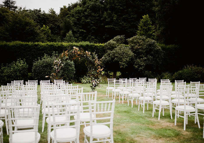 chairs set up on grass with arch in front of them for wedding ceremony