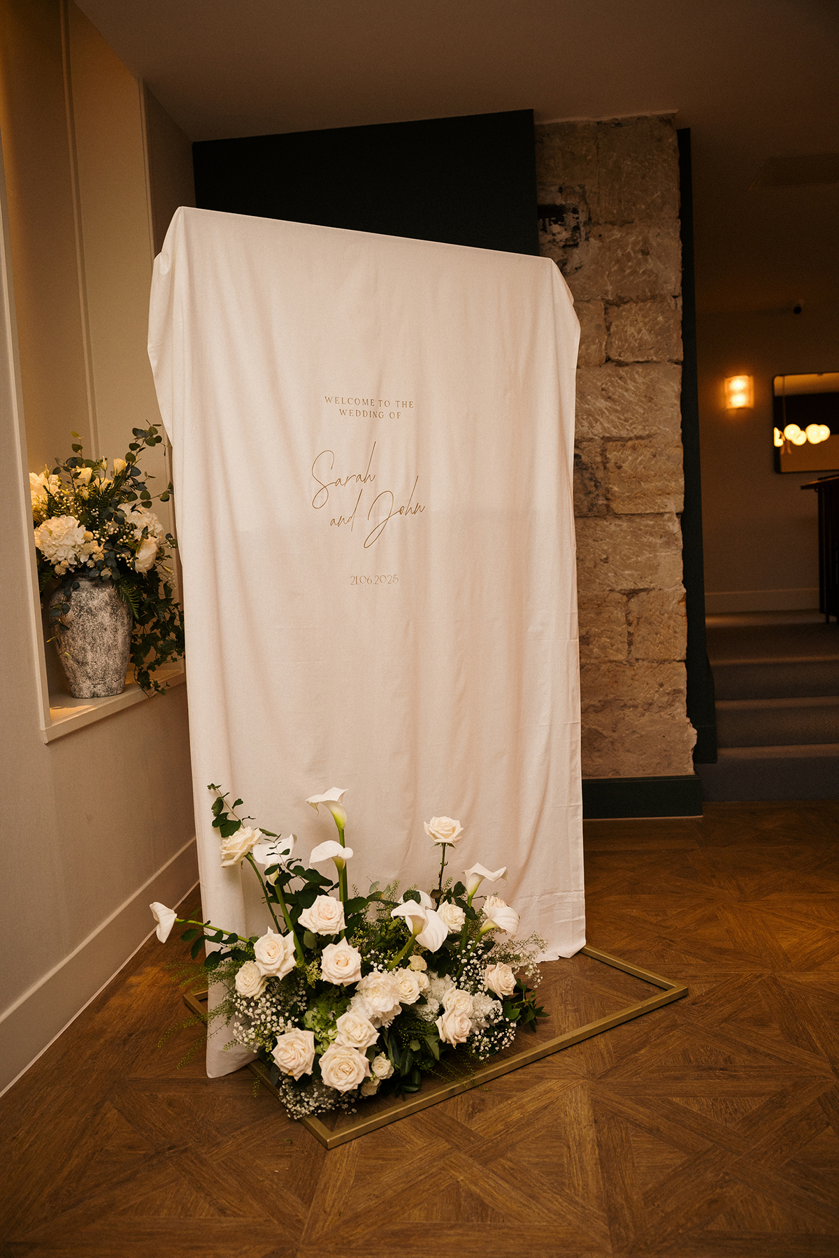 Personalised wedding welcome sign with white roses and calla lilies at a modern wedding venue