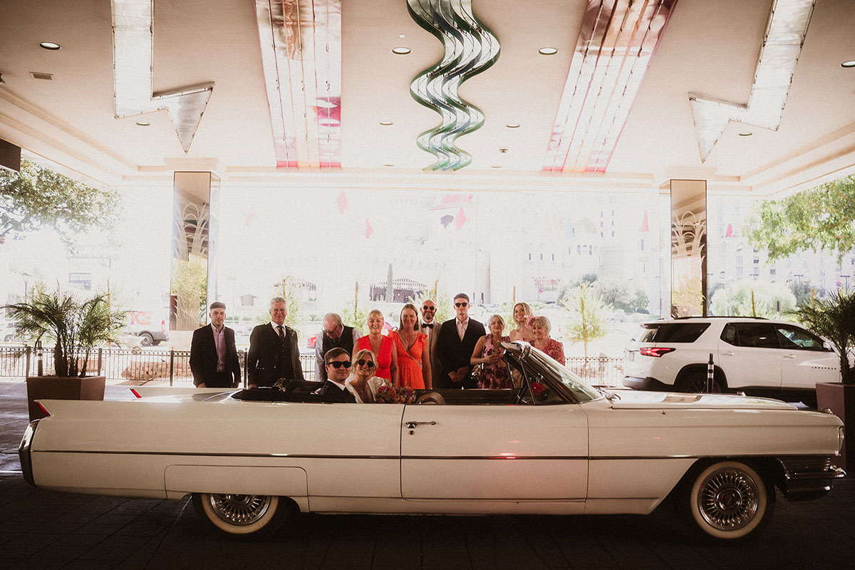 bride and groom smile in vintage car with wedding guests and ceremony in Las Vegas