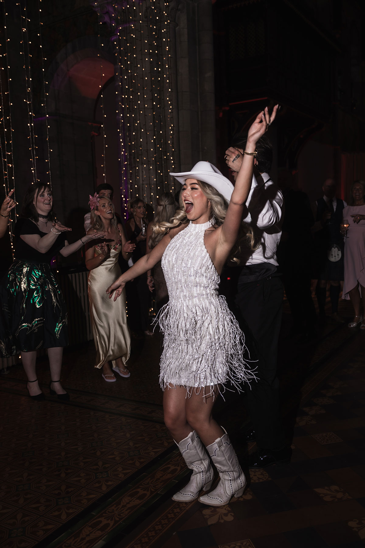 Bride in country and western inspired second wedding dress and cowboy boots on dancefloor