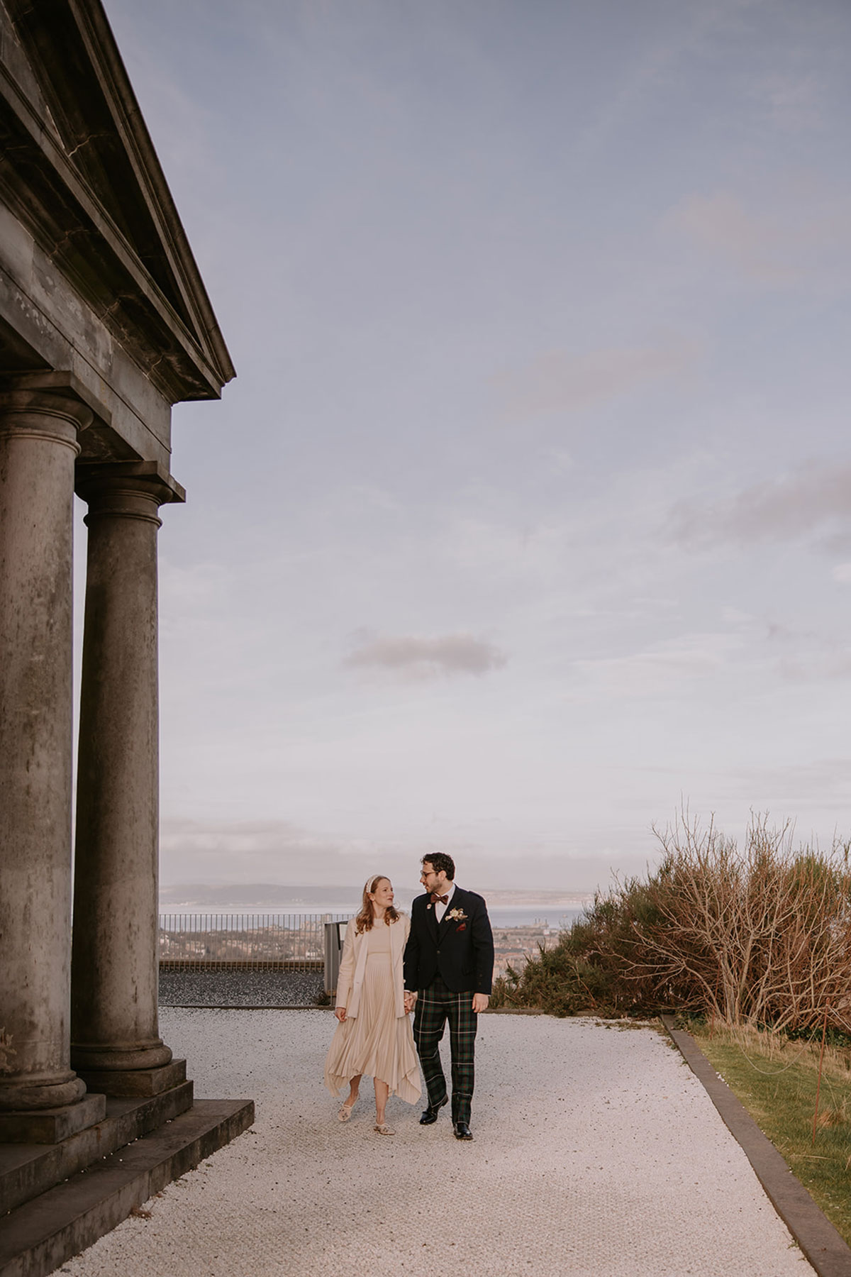 Couple walking hand in hand outside The Collective Edinburgh with city views in the background