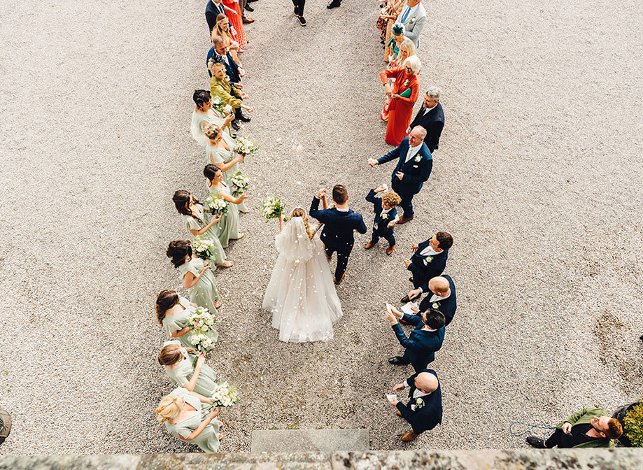Overhead view of bride and groom funneling out from their ceremony to have flower petals thrown at them