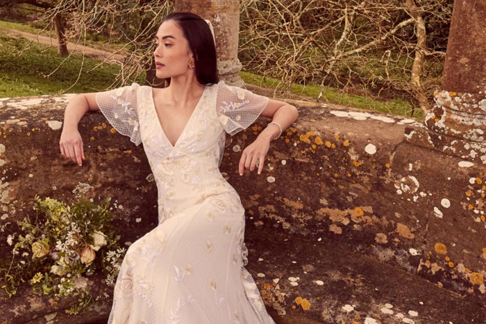 woman in cream coloured wedding dress with flower embroidery, v-neckline and fluttery cap sleeves