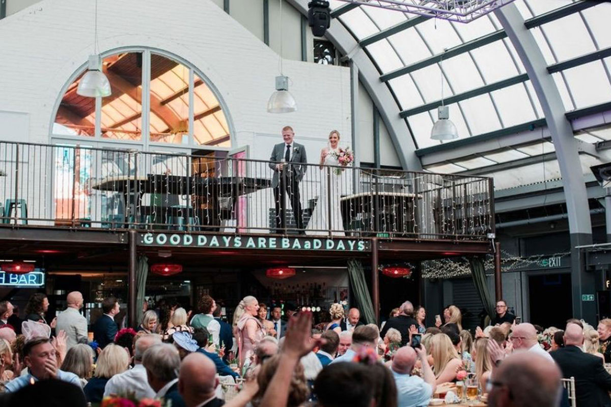 bride and groom stand on balcony at BAad and wave towards wedding guests