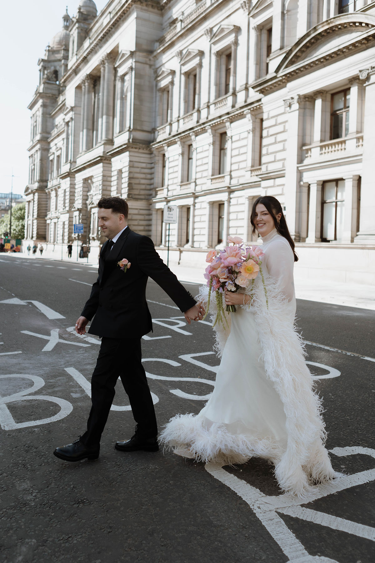 Bride and groom walking through Glasgow city centre after their wedding ceremony