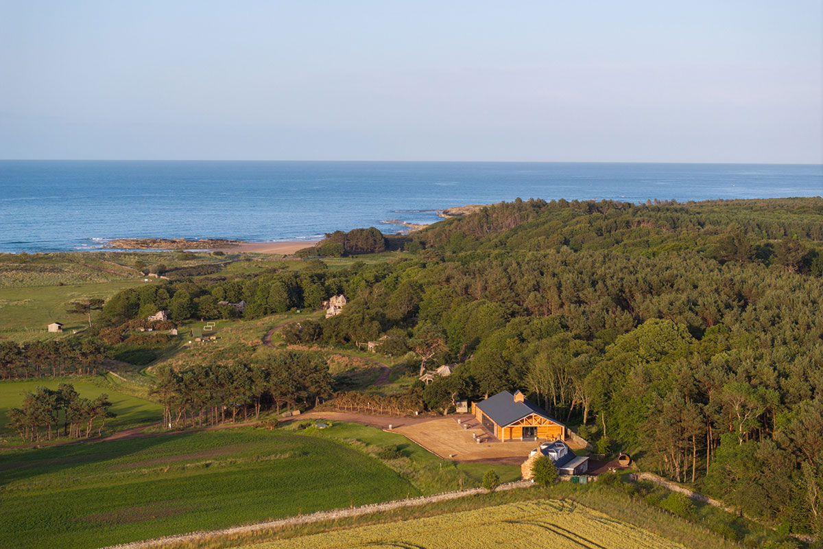 Aerial view of Harvest Moon Weddings estate with woodland, fields and the East Lothian coast