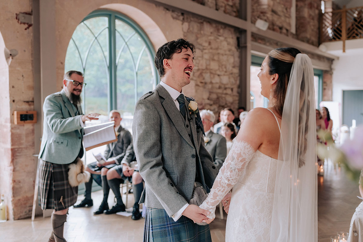 couple laugh during wedding ceremony at broxmouth as celebrant reads out loud