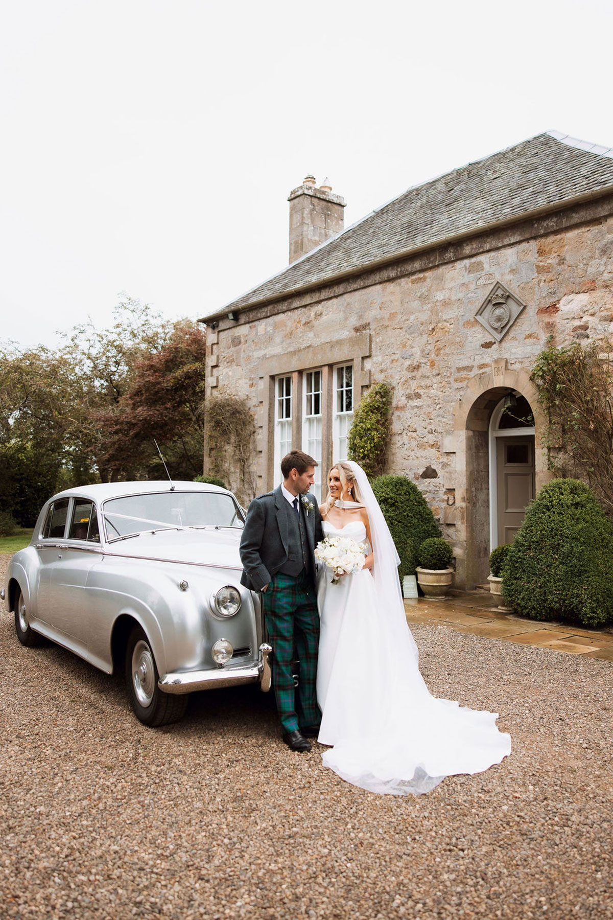 Bride and groom beside vintage wedding car outside Rosebery House Edinburgh