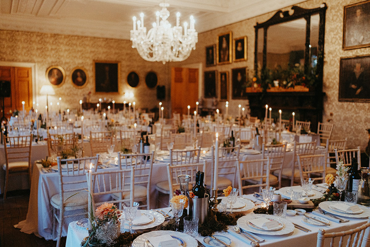 Elegant reception set-up inside Cambo Country House, with candlelit tables, crystal chandelier and autumn-inspired floral styling for a Fife wedding.