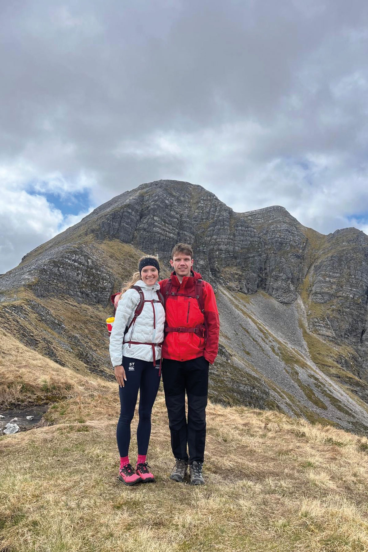 two people wearing hillwalking attire posing with a Scottish mountain in the background