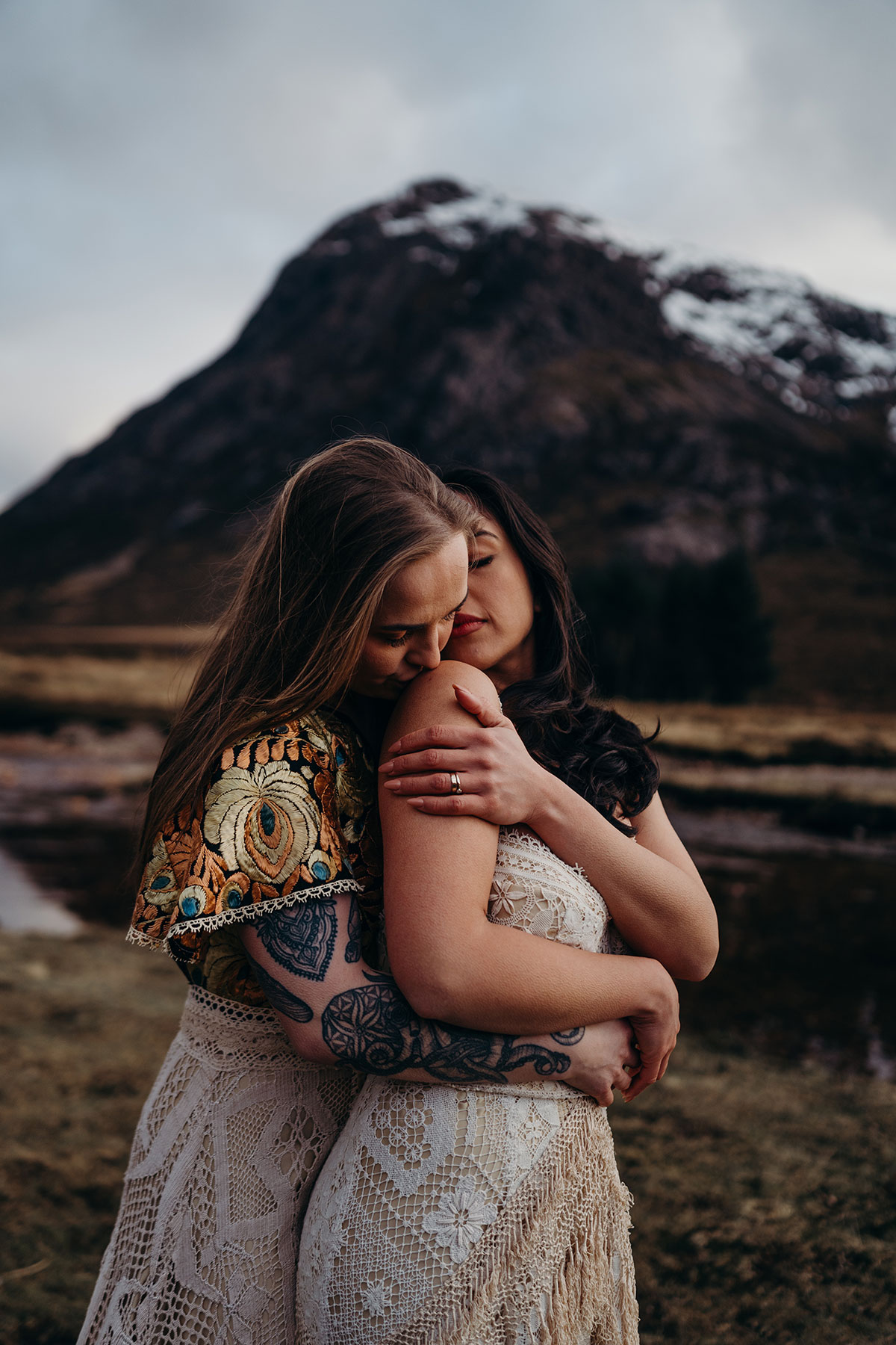 Intimate portrait of a couple embracing during a Scottish elopement shoot in Glencoe, with mountains behind them.