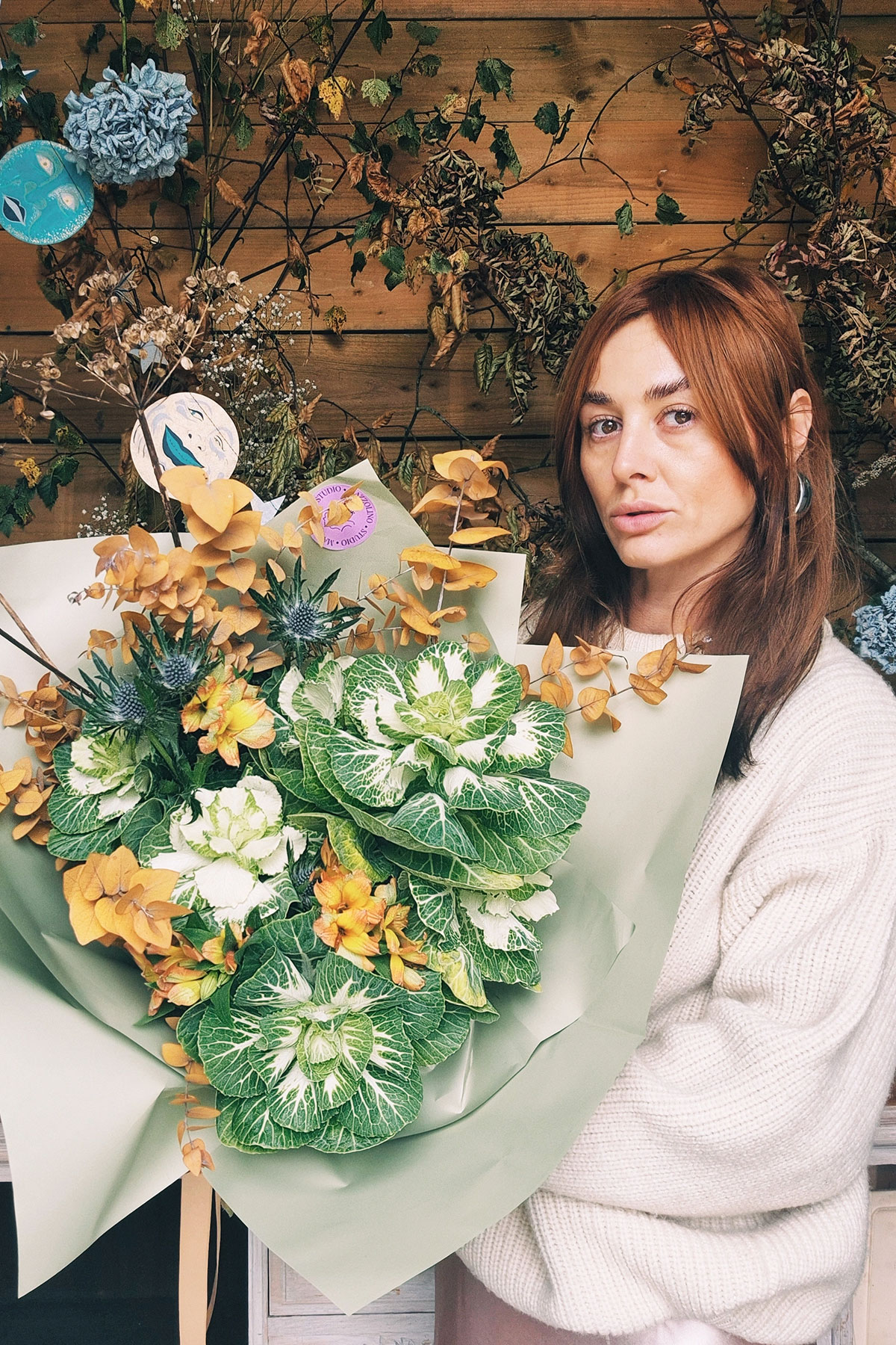 Levi Macdonald Studio Mazzolino florist – Florist Levi Macdonald holding large bouquet of peach, white and green flowers.