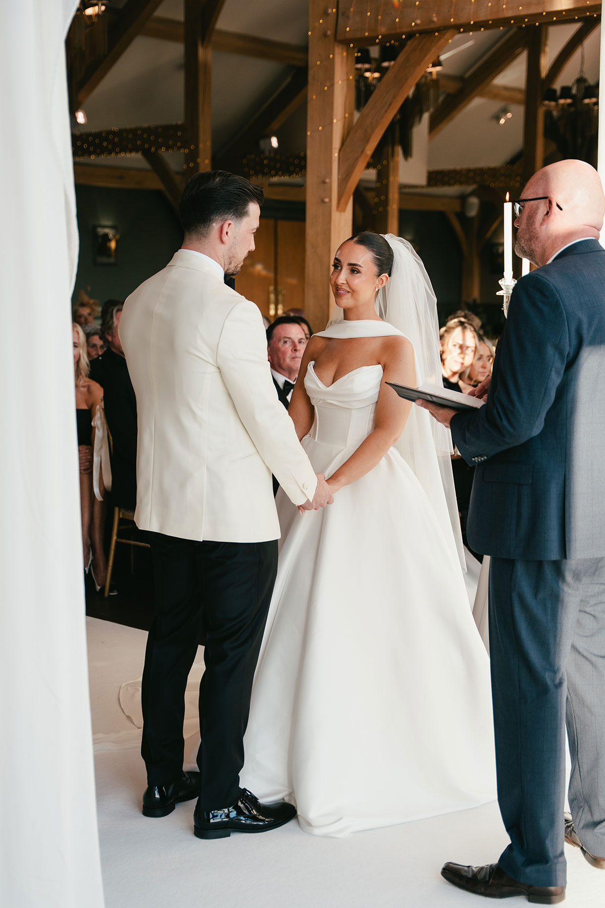 Bride and groom exchanging vows during wedding ceremony at Enterkine Country House Resort Ayrshire with guests watching
