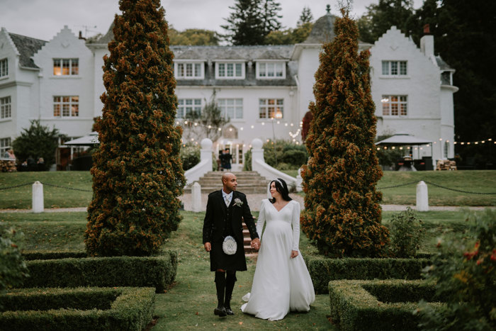 bride and groom walking hand in hand away from achnagairn castle on wedding day
