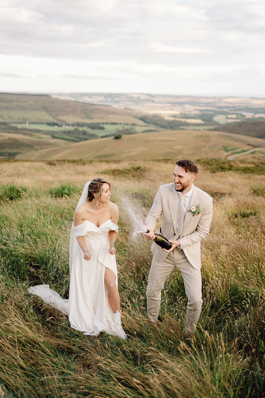 bride and groom pop champagne outdoors in scotland