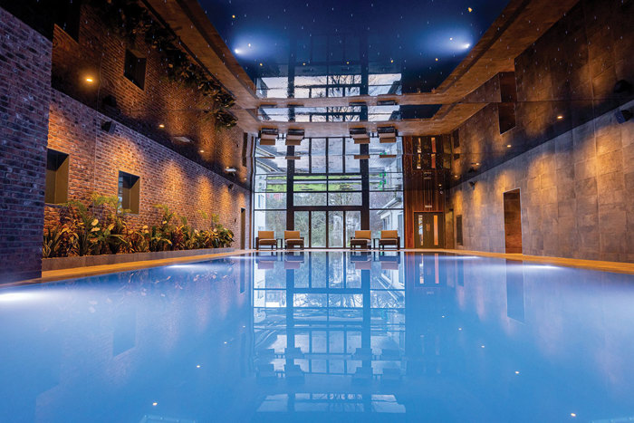 A spa swimming pool lit up with ambient lighting on the ceiling above