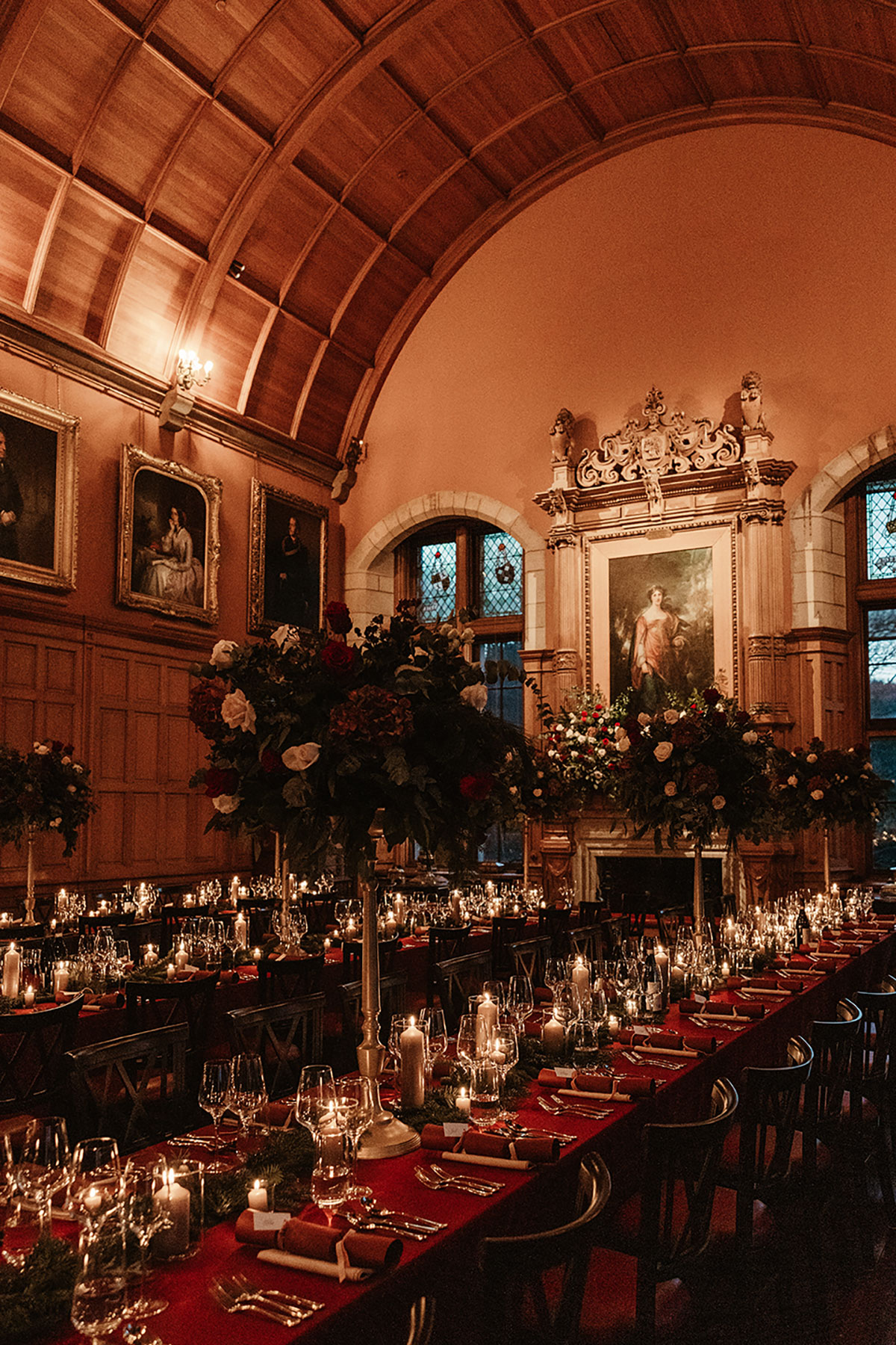 Grand hall at Barnbougle Castle with arched wooden ceiling, festive floral centrepieces and long candlelit tables set for a Christmas wedding.