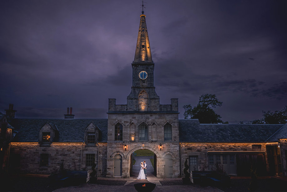 a couple standing in the archway of a stone building at night