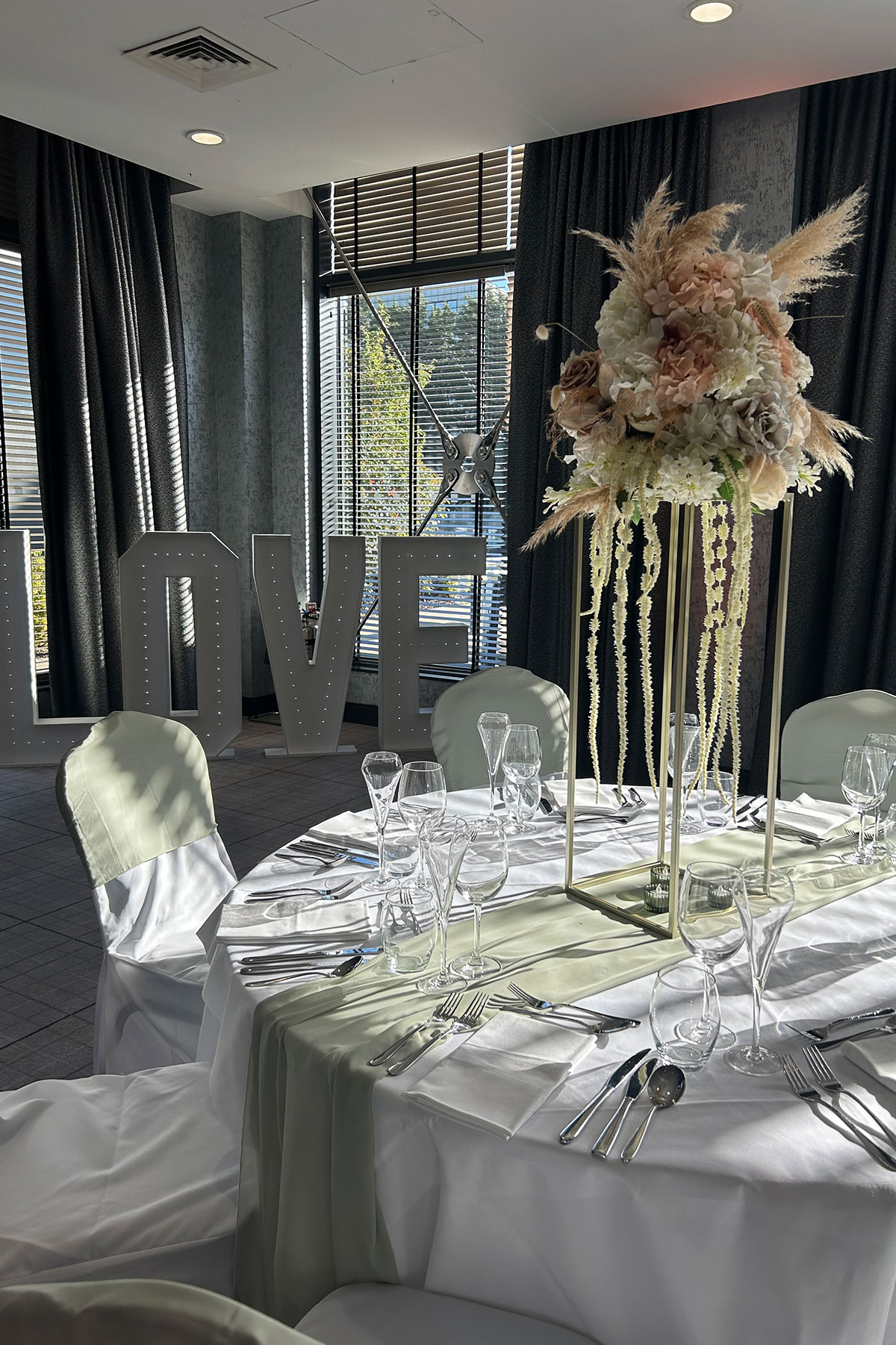 Wedding breakfast styling with tall floral centrepiece, illuminated LOVE letters and elegant table décor at a Scottish wedding venue