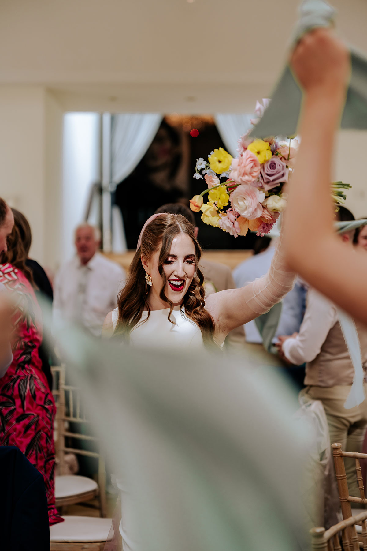 a cheering bride holding a colourful bouquet of flowers during wedding reception at Carlowrie Castle