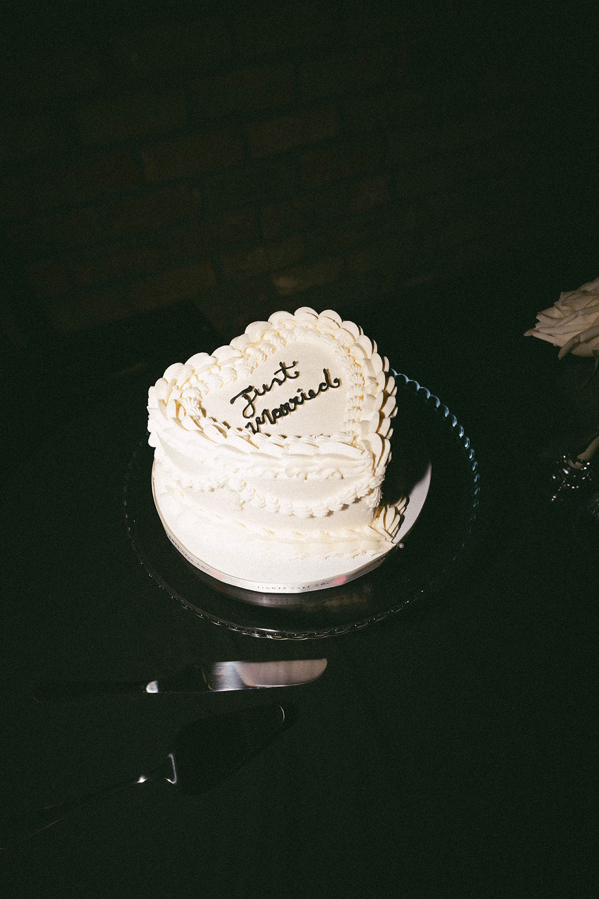 close up of vintage style just married wedding cake on black table