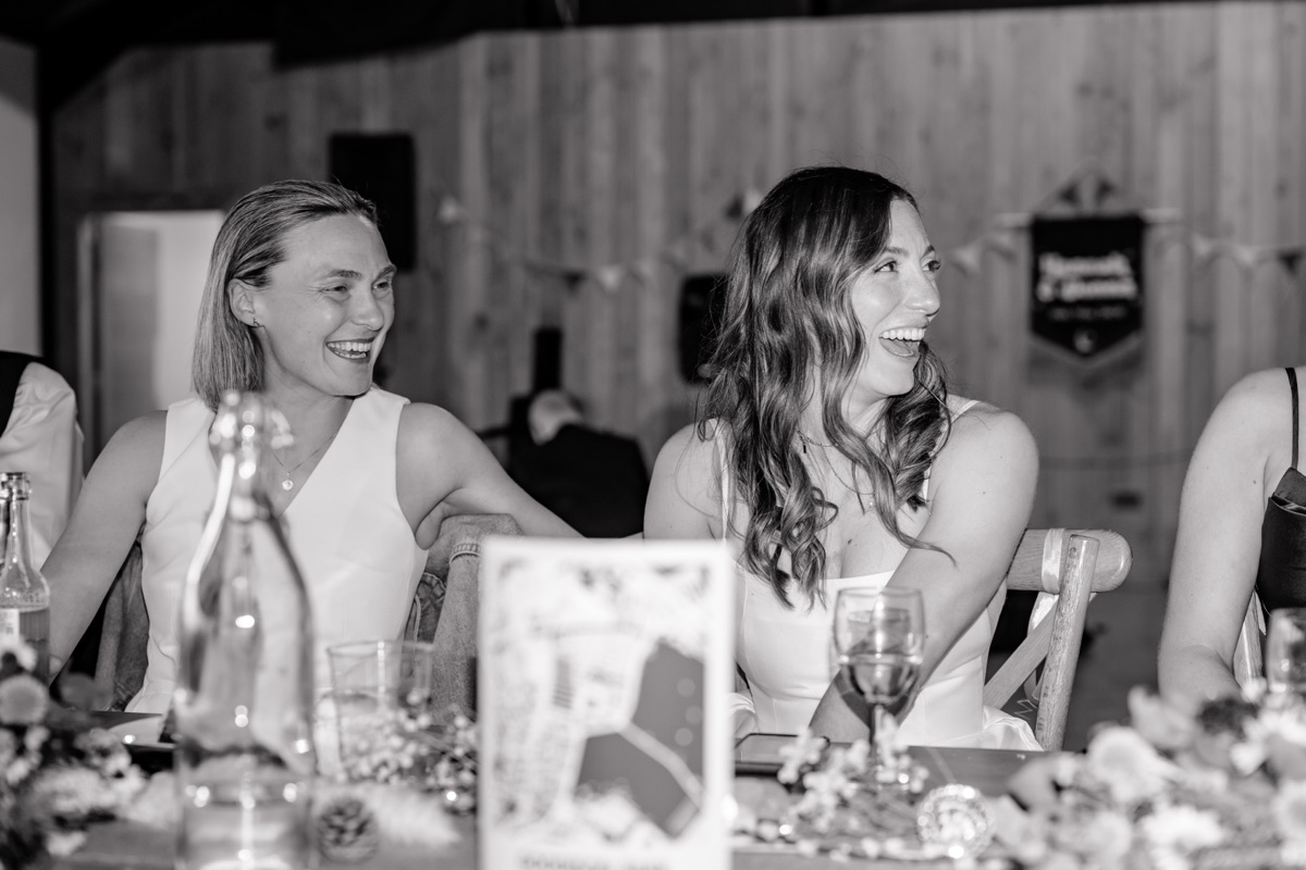 Black-and-white photo of Hannah and Donna laughing together at their Harvest Moon wedding reception.