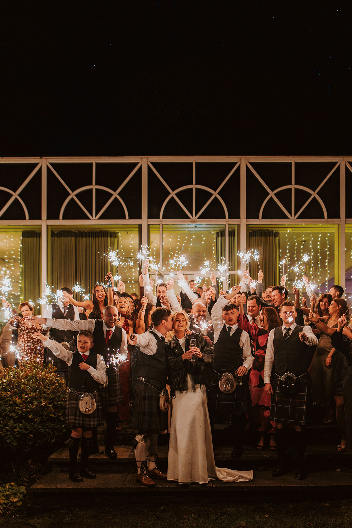 bride and groom smile with their guests holding sparklers during wedding at Ardoe House