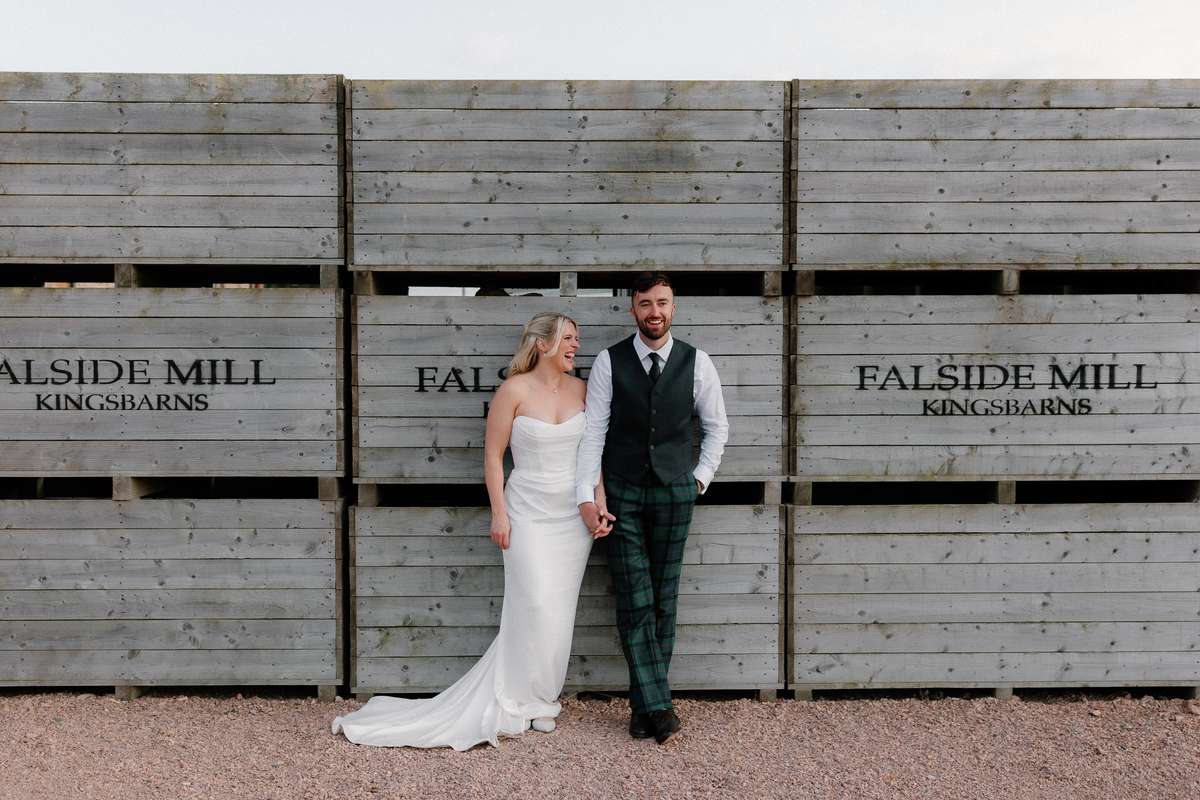Bride and groom walking hand in hand outside Falside Mill wedding venue in Kingsbarns, Fife