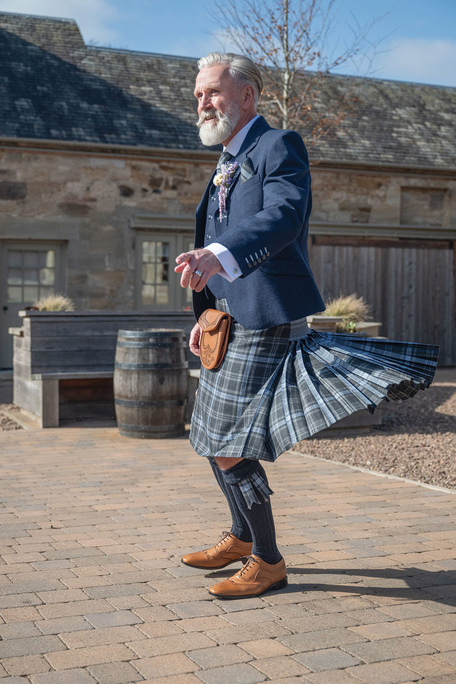 a man twirling in a blue tartan kilt outfit from Eight Yards