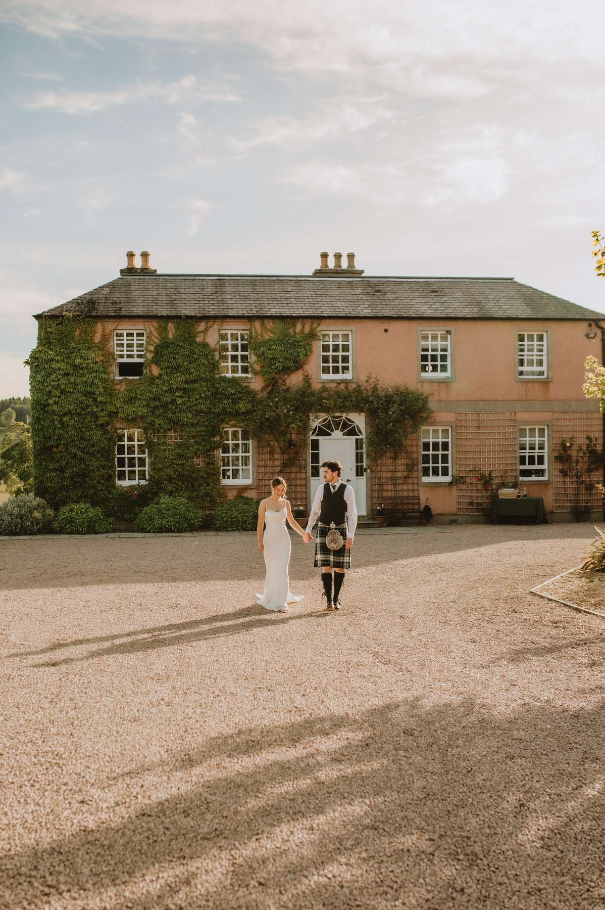 Bride and groom embrace beside the ivy-covered exterior of Ballogie House after their wedding