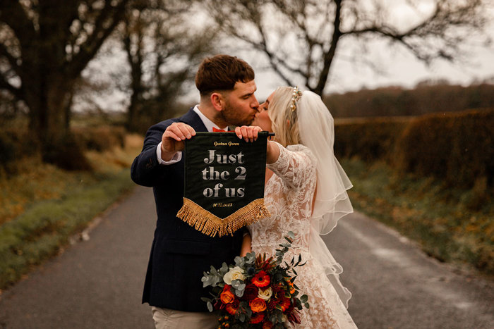 Couple elope to Gretna Green in Dumfriesshire holding up sign and kissing