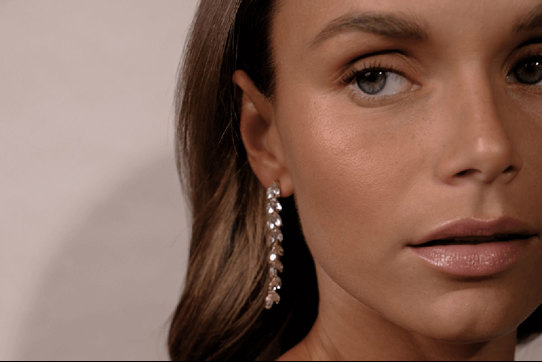a model wearing long sparkling crystal leaf earrings