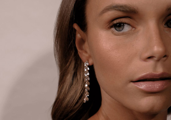 a model wearing long sparkling crystal leaf earrings