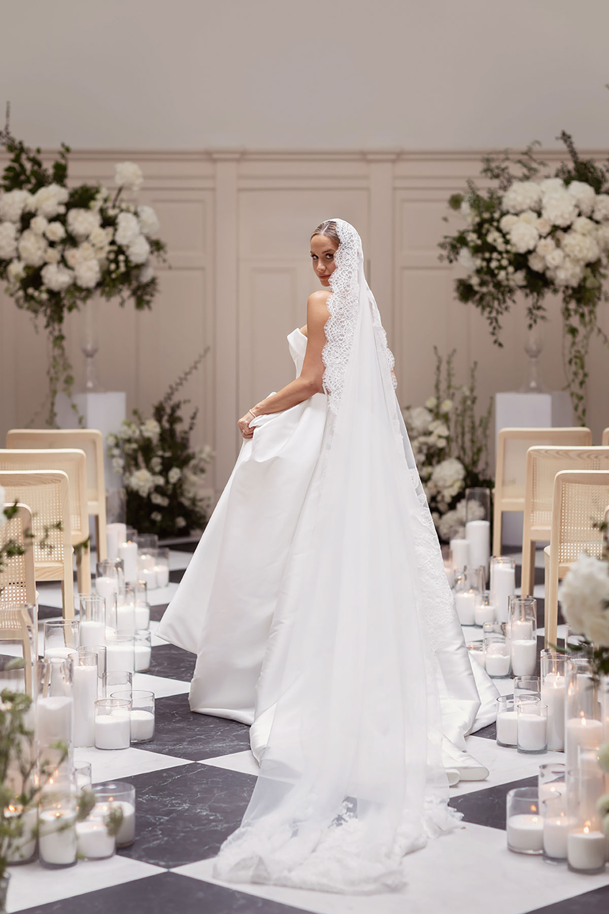 Bride in a strapless satin wedding gown with a lace-edged veil, standing in a candlelit aisle at The Collector’s Hall in Glasgow