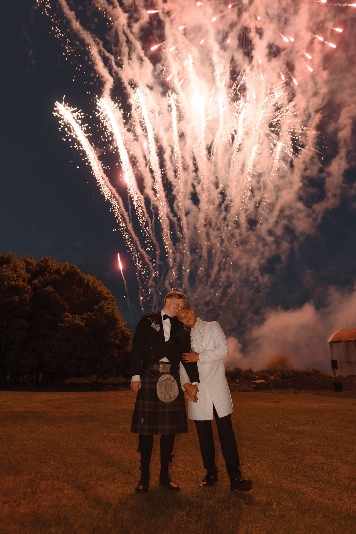 Two grooms sharing a quiet moment during evening reception at DIY farm wedding in Falkirk