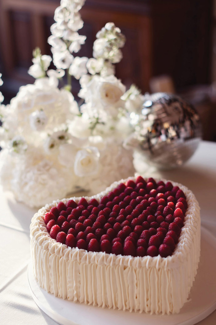 A cake in the shape of a heart with raspberries.