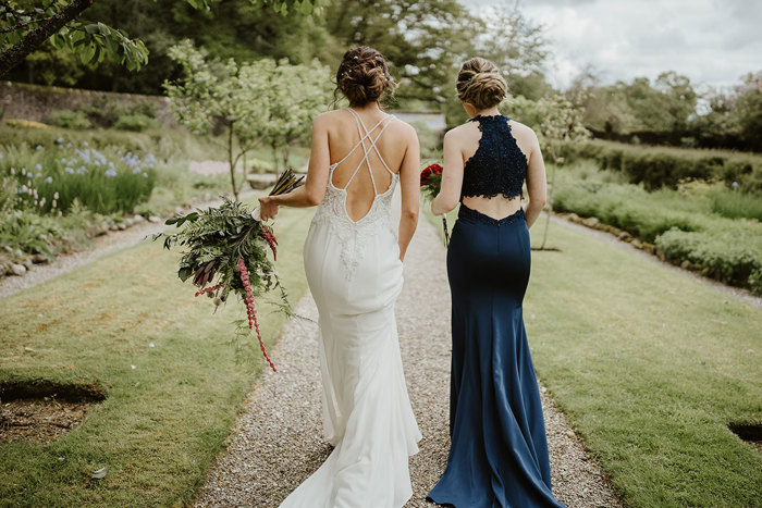 Bride and bridesmaid walk through garden