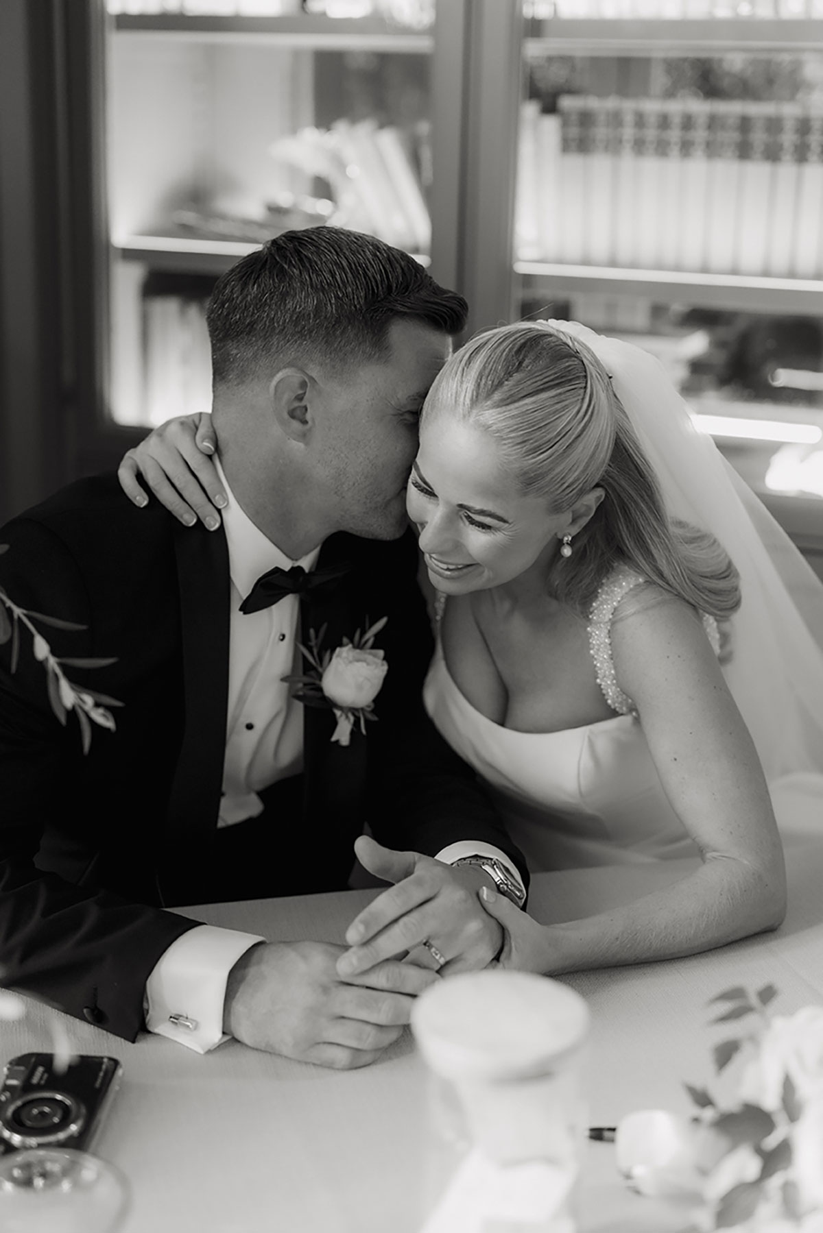 Black-and-white image of the newlyweds sharing a quiet moment while signing the marriage schedule.