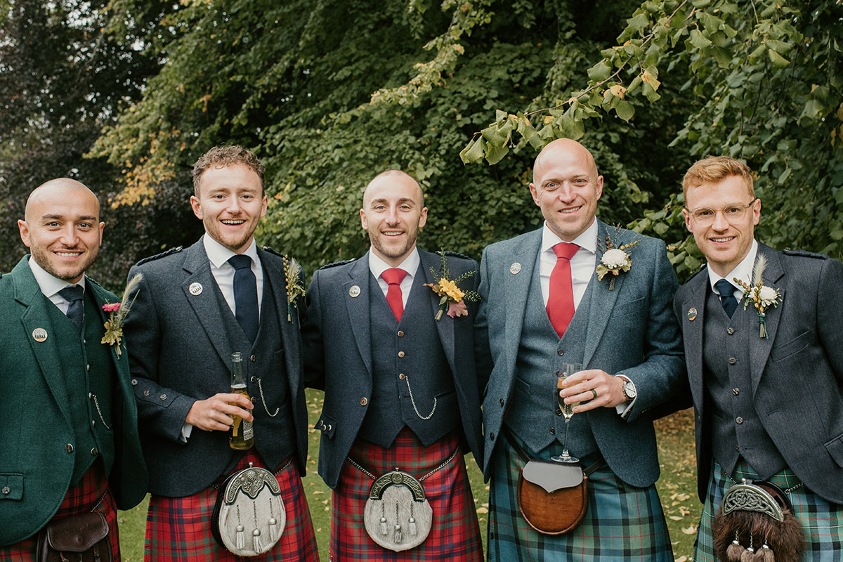 groom and groomsmen wearing kilts in garden at Achnagairn Castle