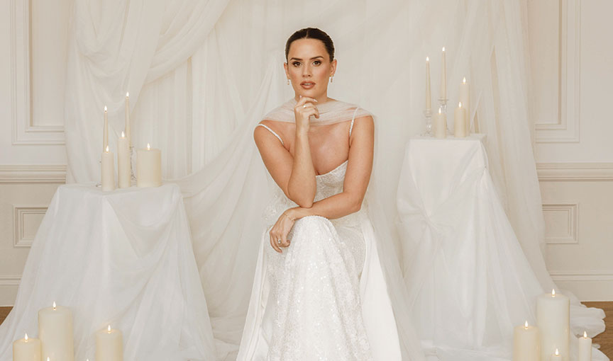 Bride seated in an elegant white gown by Opus Couture surrounded by soft draping and tall ivory candles at The Exchange Glasgow.