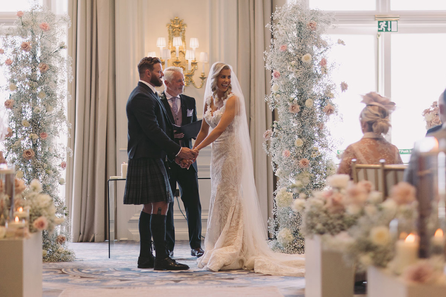 Bride and groom hold hands during the ceremony