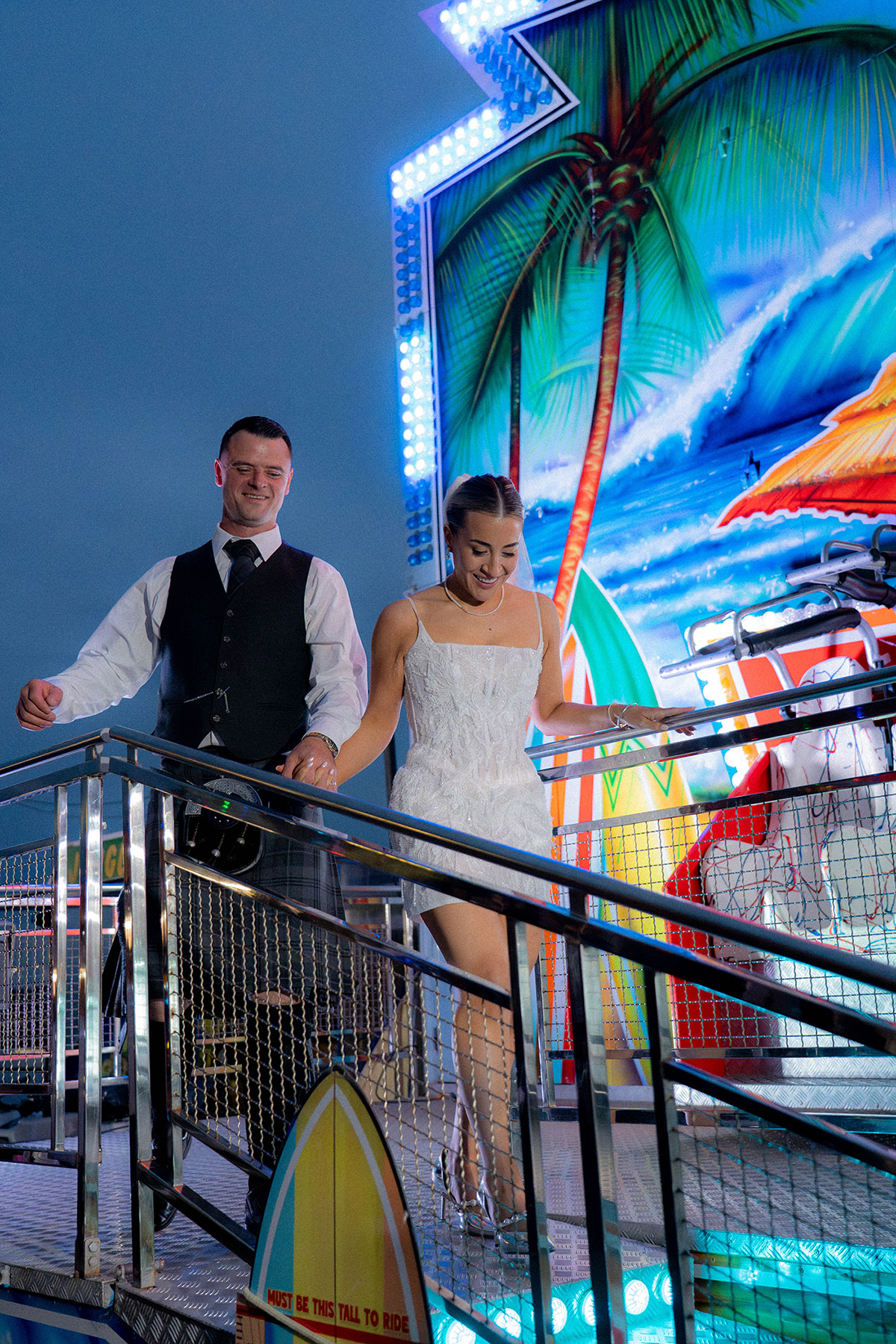 Bride and groom stepping onto fairground ride during evening celebrations at Brisbane House Hotel wedding