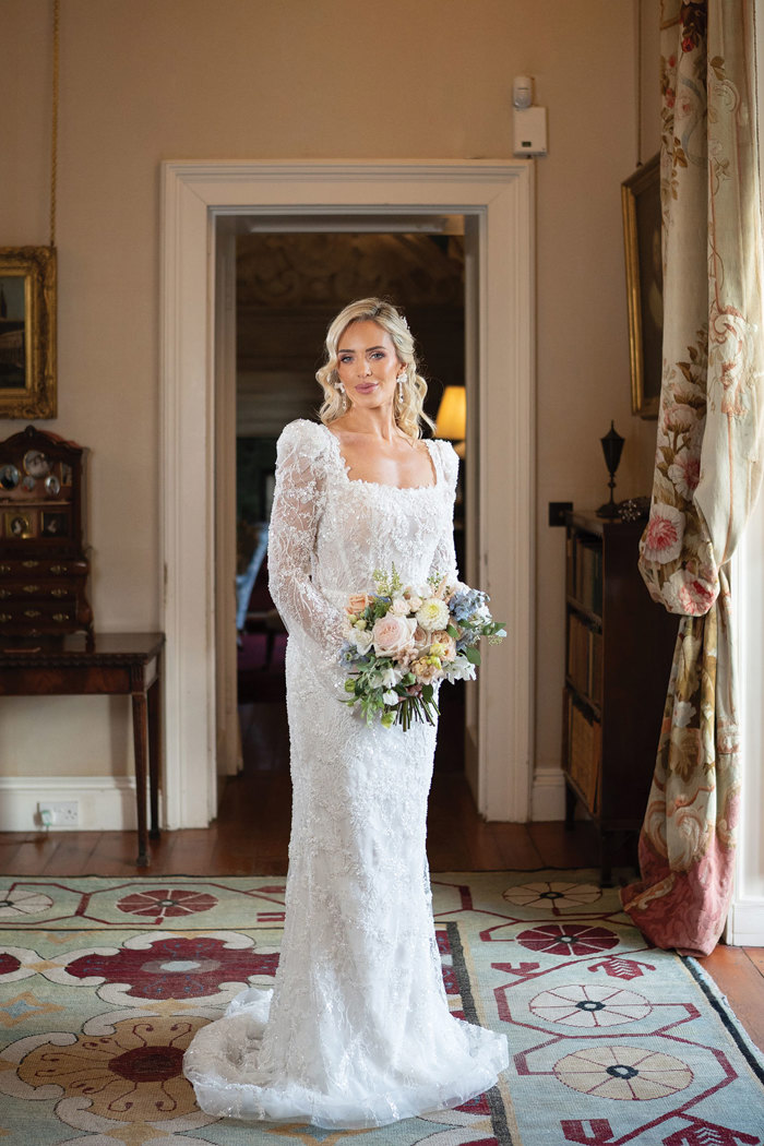 A blonde bride wearing an embellished lace square-neck, puff sleeve wedding dress 