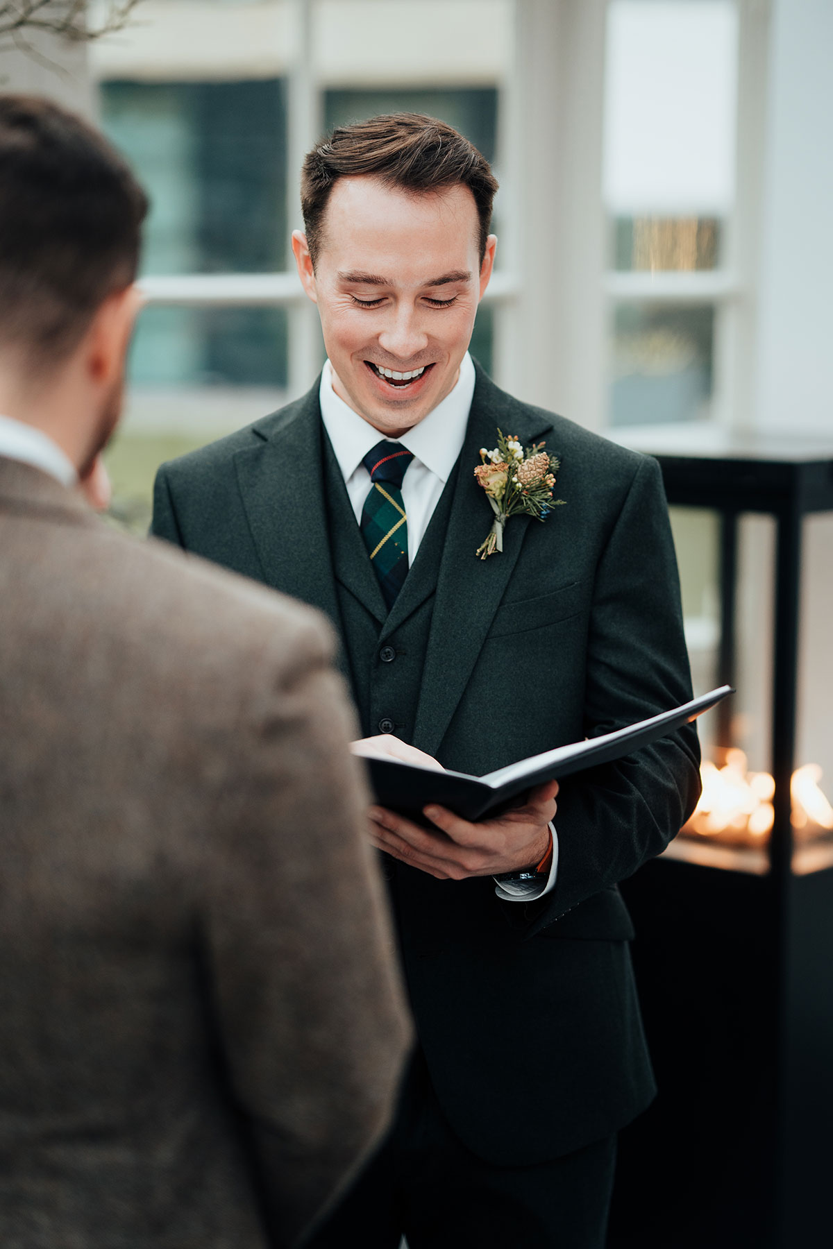 Groom smiling as he reads his vows during the wedding ceremony