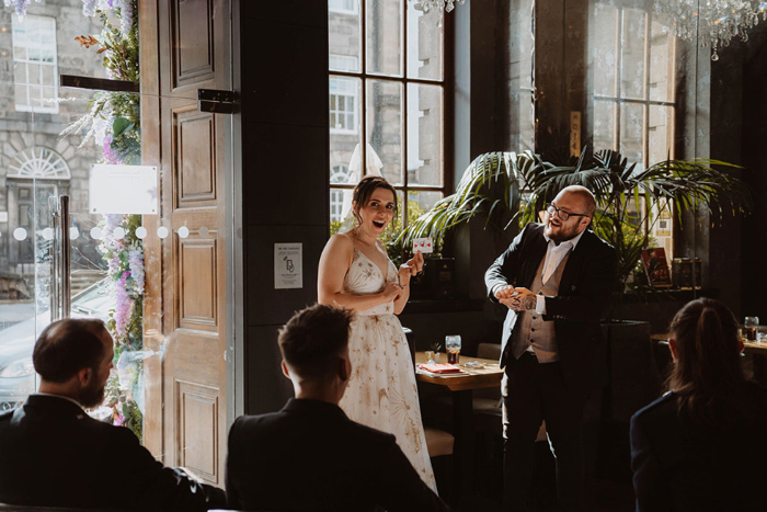 Bride looks surprised at magic trick performed during drinks reception