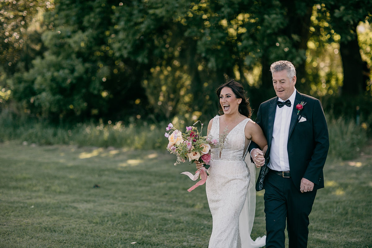 Bride walking with her father before an outdoor wedding ceremony at Boschendal Wine Estate in Cape Town, South Africa
