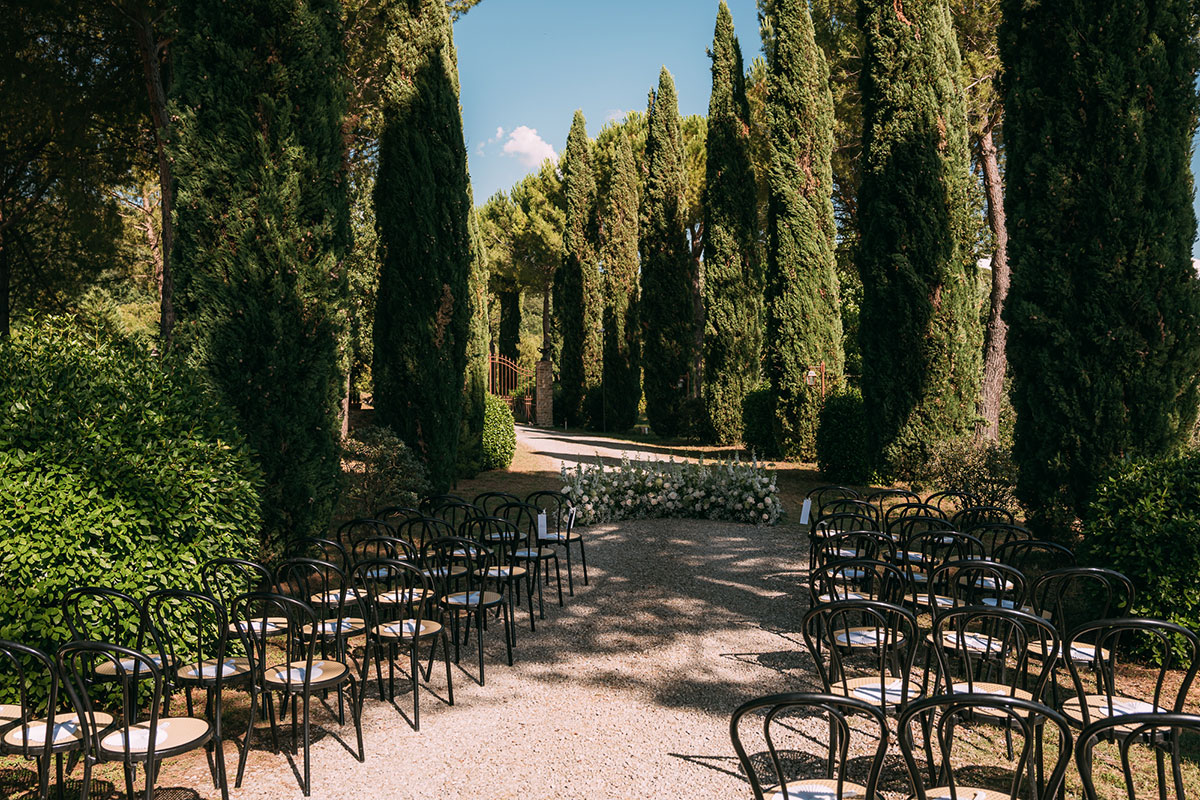 Outdoor wedding ceremony setup with chairs among cypress trees at Antico Borgo San Lorenzo Tuscany