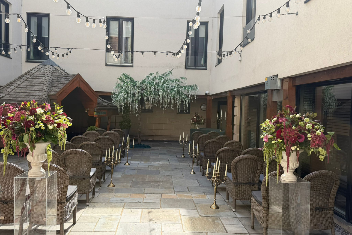 Outdoor wedding ceremony at Hotel du Vin Edinburgh with wicker chairs, floral arrangements and festoon lighting