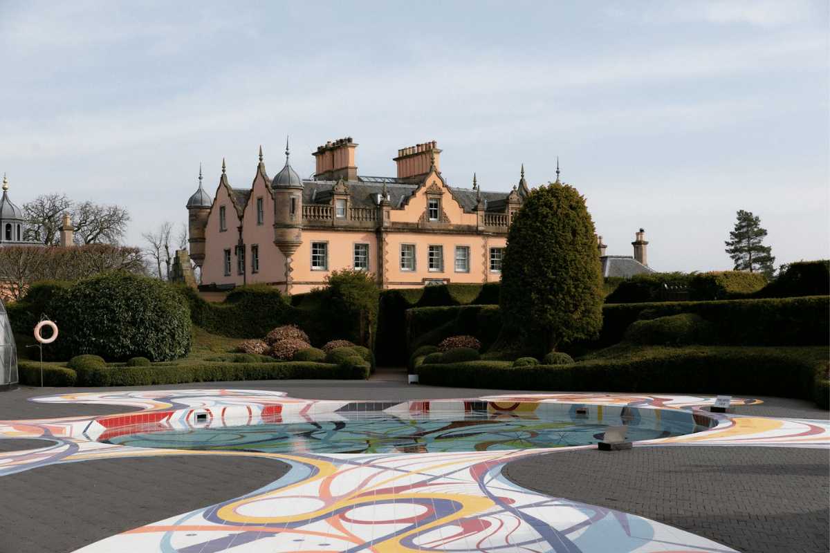 View of Jupiter Artland near Edinburgh with the historic house, landscaped gardens and colourful artwork surrounding the pool
